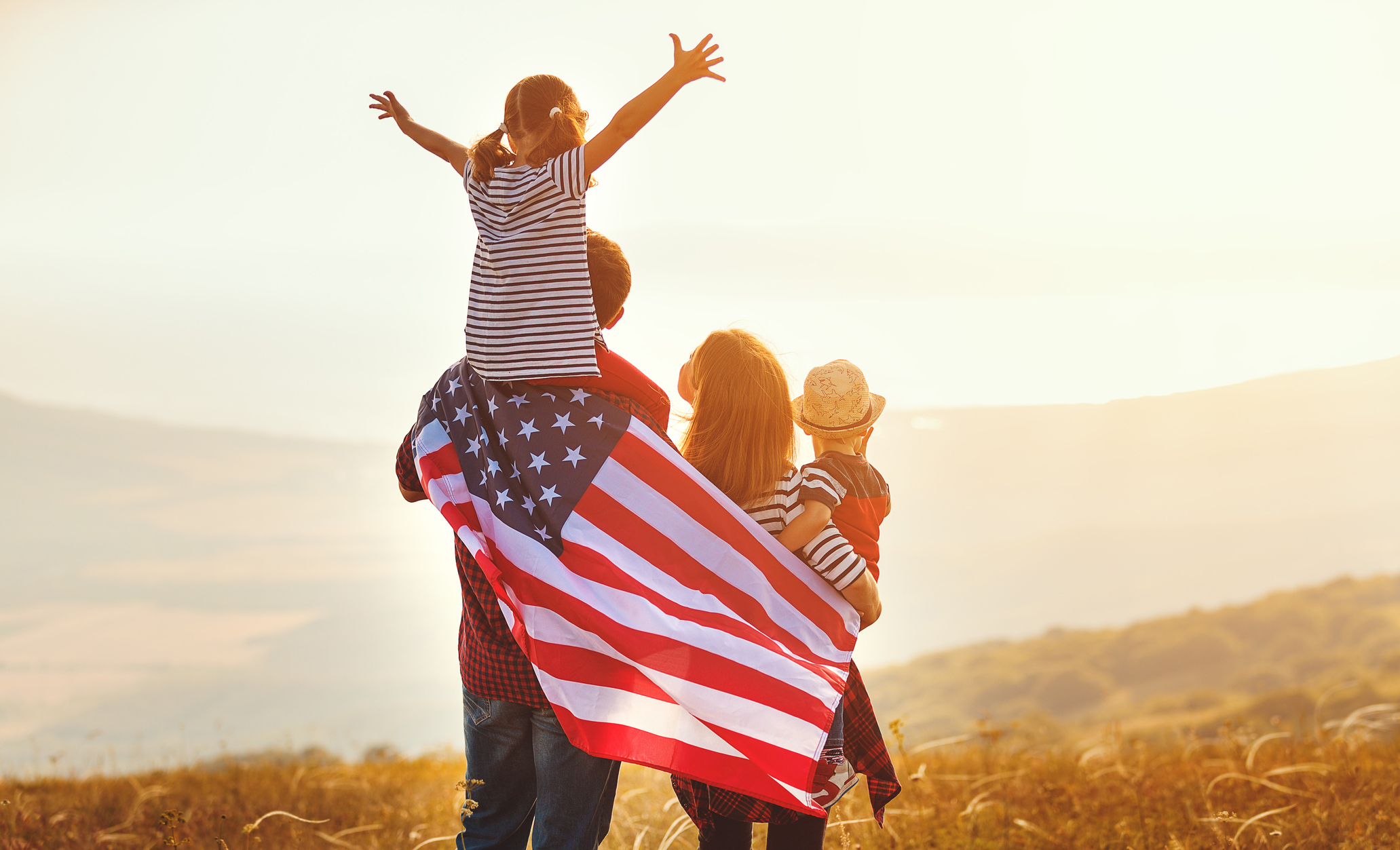 happy family with flag of america USA at sunset outdoors
