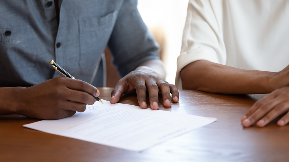 African man putting signature on agreement close up image