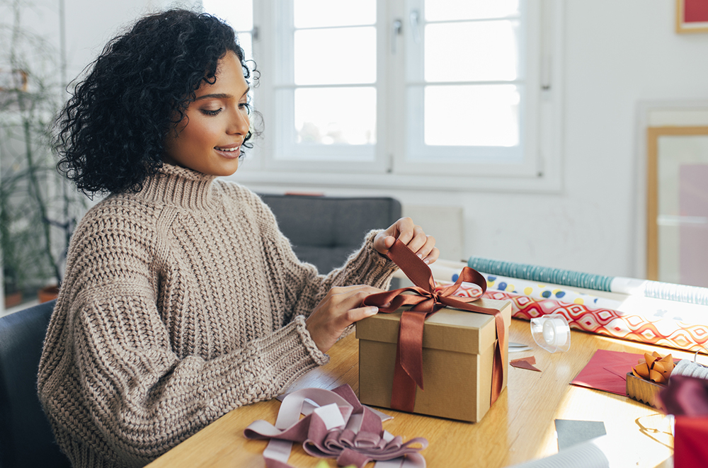 Getting Ready for Christmas: a Happy Young Woman Packing Christmas Presents for her Loved Ones