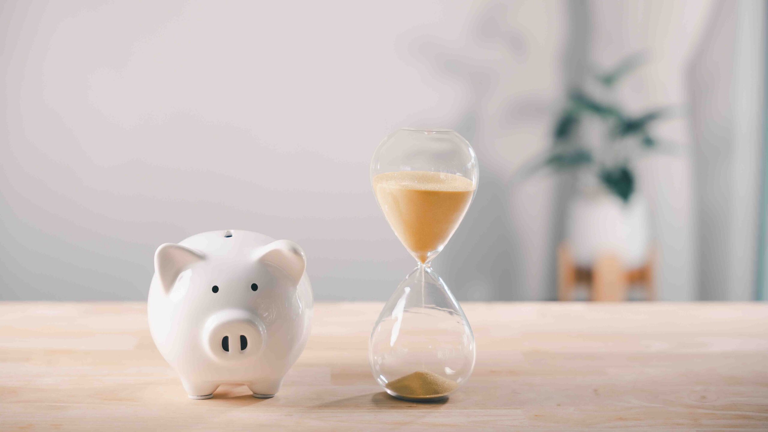 Image of an hourglass next to a piggy bank