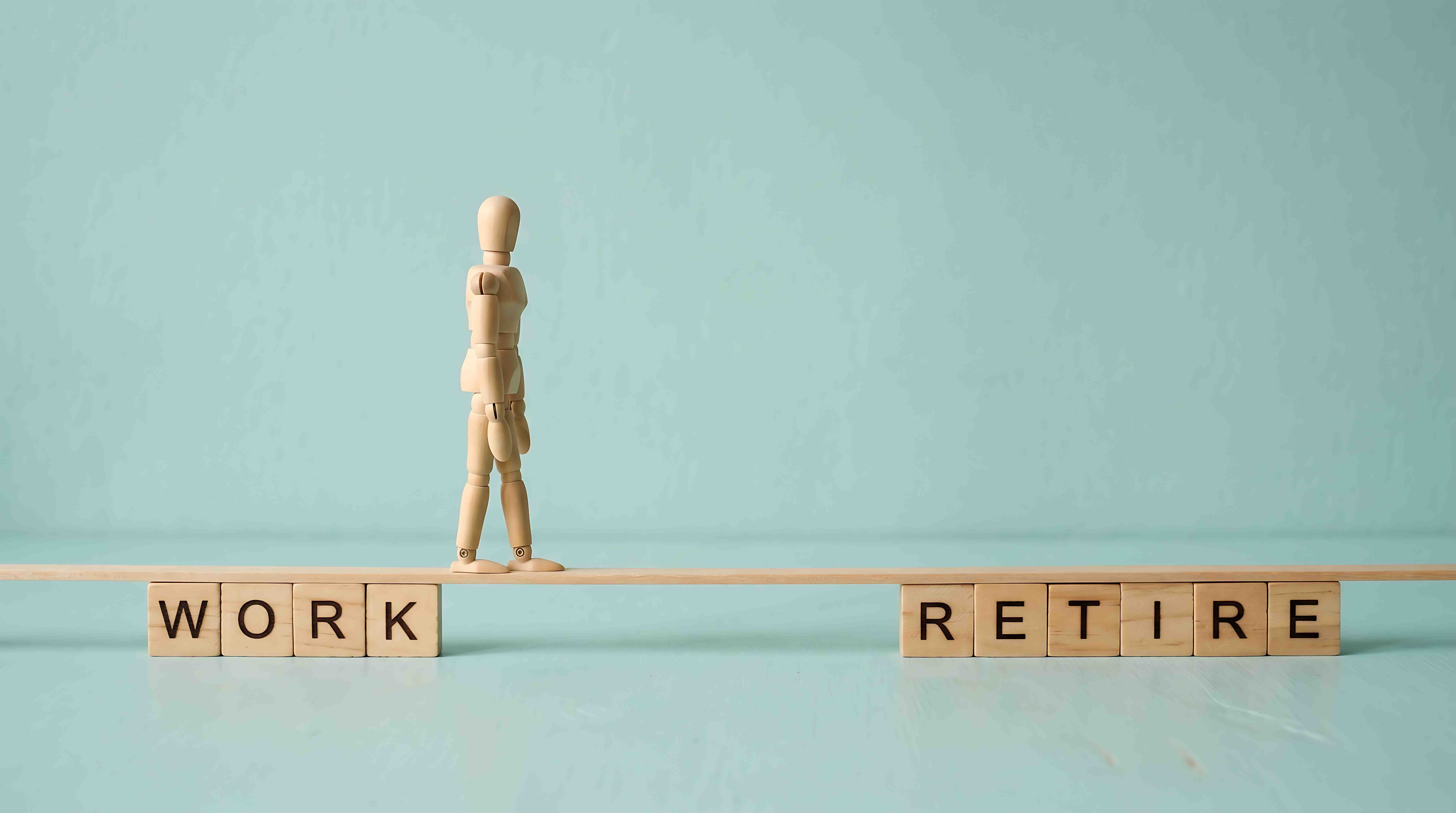 Wooden mannequin walking on a narrow plank between the concepts of work and retirement life goals